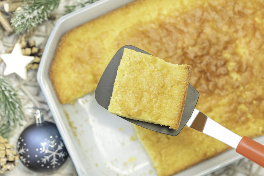 a slice of cheesy cornbread being taken out of the pan