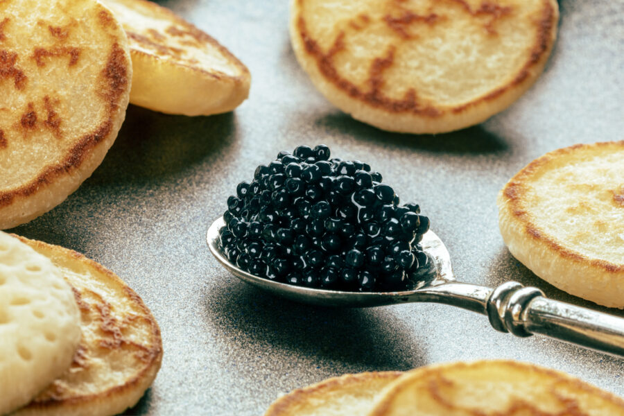 Silver spoon with caviar closeup with blinis