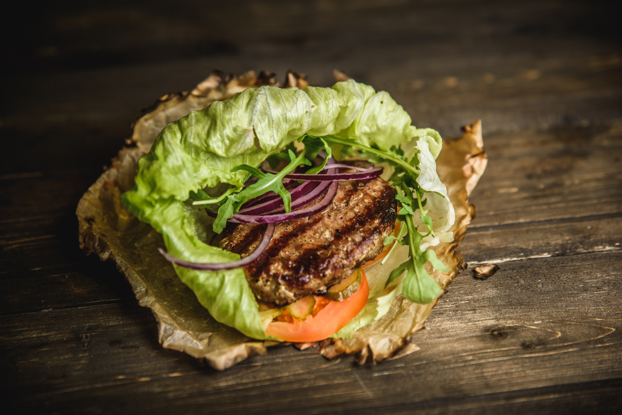 the Burger on the burnt paper on wooden background