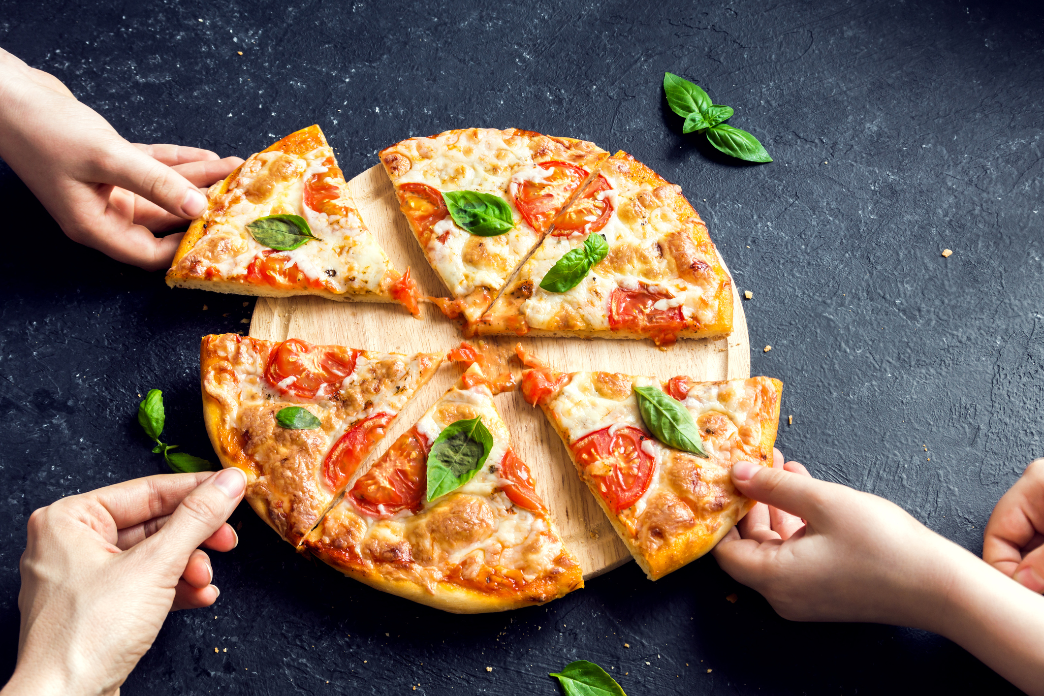 People Hands Taking Slices Of Pizza Margherita. Pizza Margarita and Hands close up over black background.