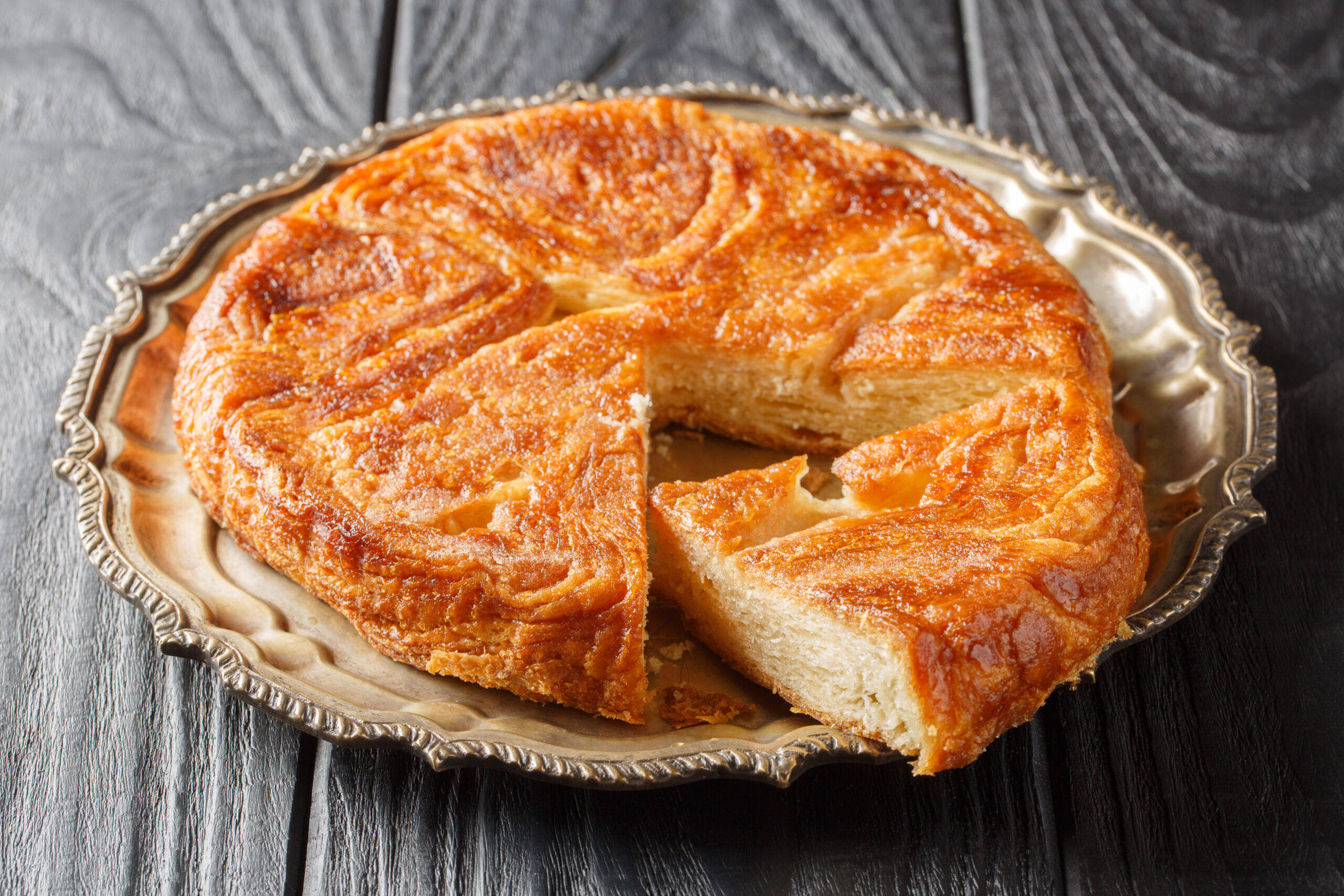 Kouign Amann is a pastry made with a lot of butter from the Brittany region of France closeup on the plate on the table. Horizontal