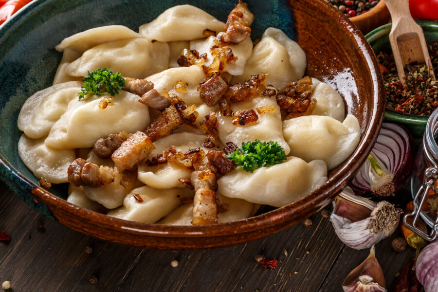 Pierogi or pyrohy, varenyky, vareniki, dumplings served with caramelized salted onion in bowl on wooden table 