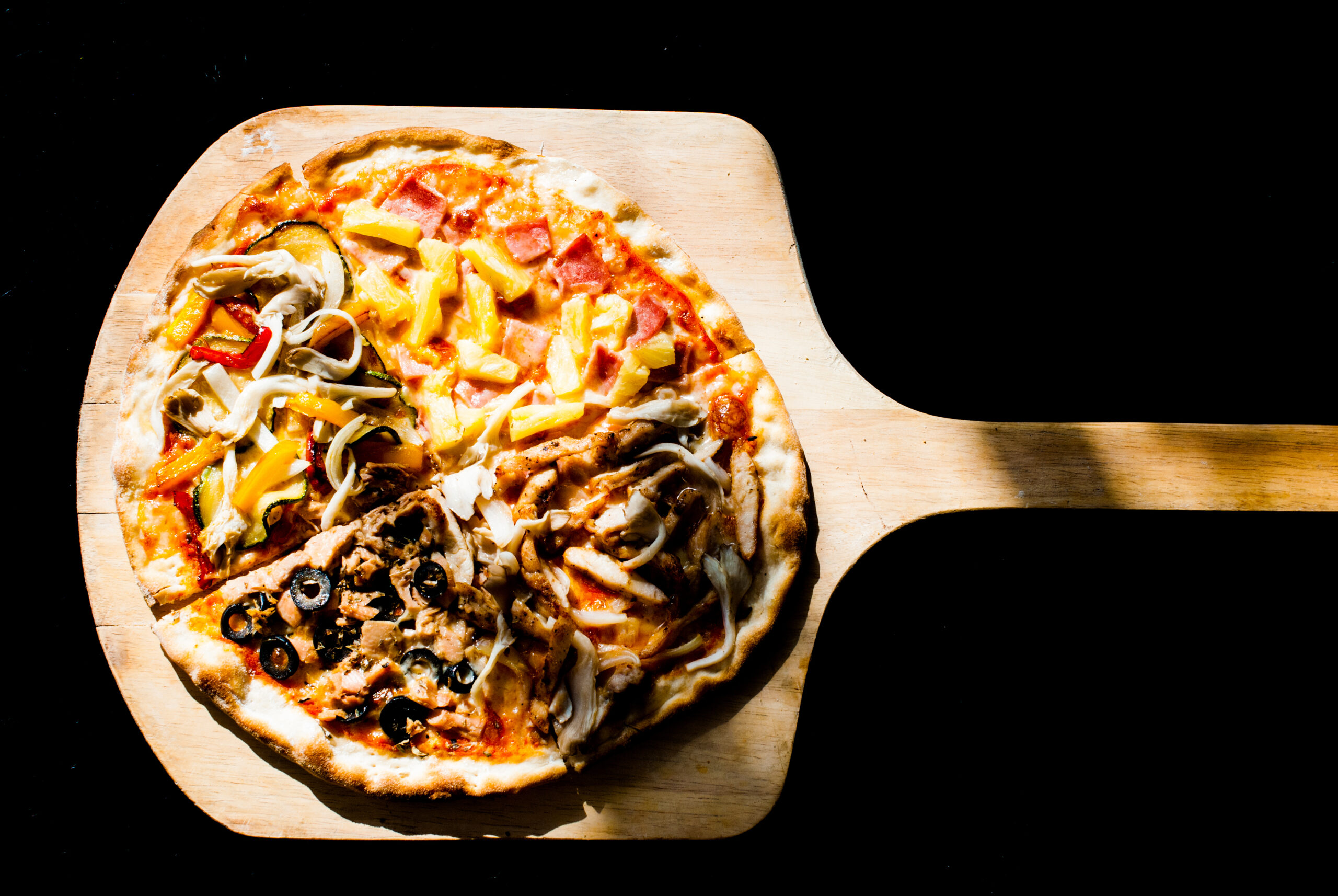 Pizza on a wooden paddle with a black background