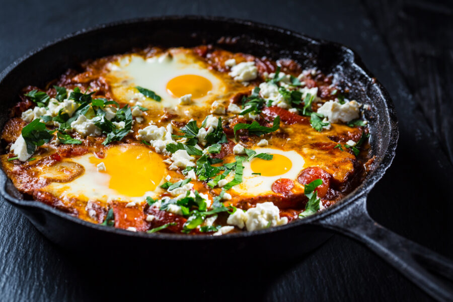 Shakshouka - Middle eastern traditional dish with poached eggs in tomato sauce with feta cheese