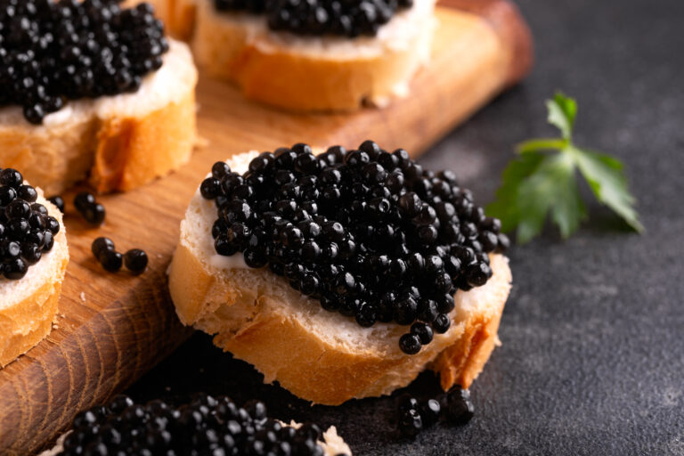 Slices of bread with black caviar on rustic dark background.