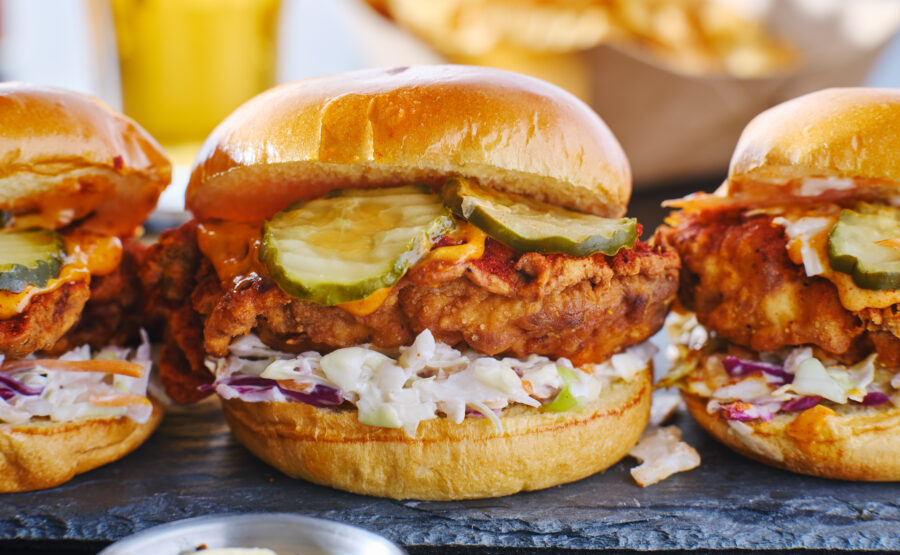 spicy nashville hot chicken sandwich with coleslaw and pickles in a row