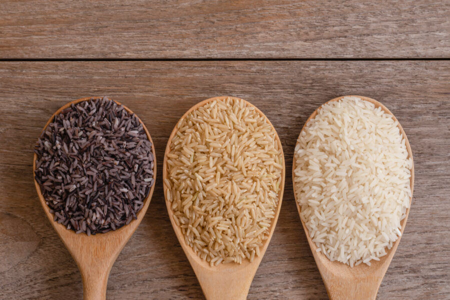 Variety type and color of rice ; paddy rice, riceberry ,brown coarse rice and white thai jasmine rice in wooden spoon isolated on old rustic wood table background. Healthy food concept. Flat lay.