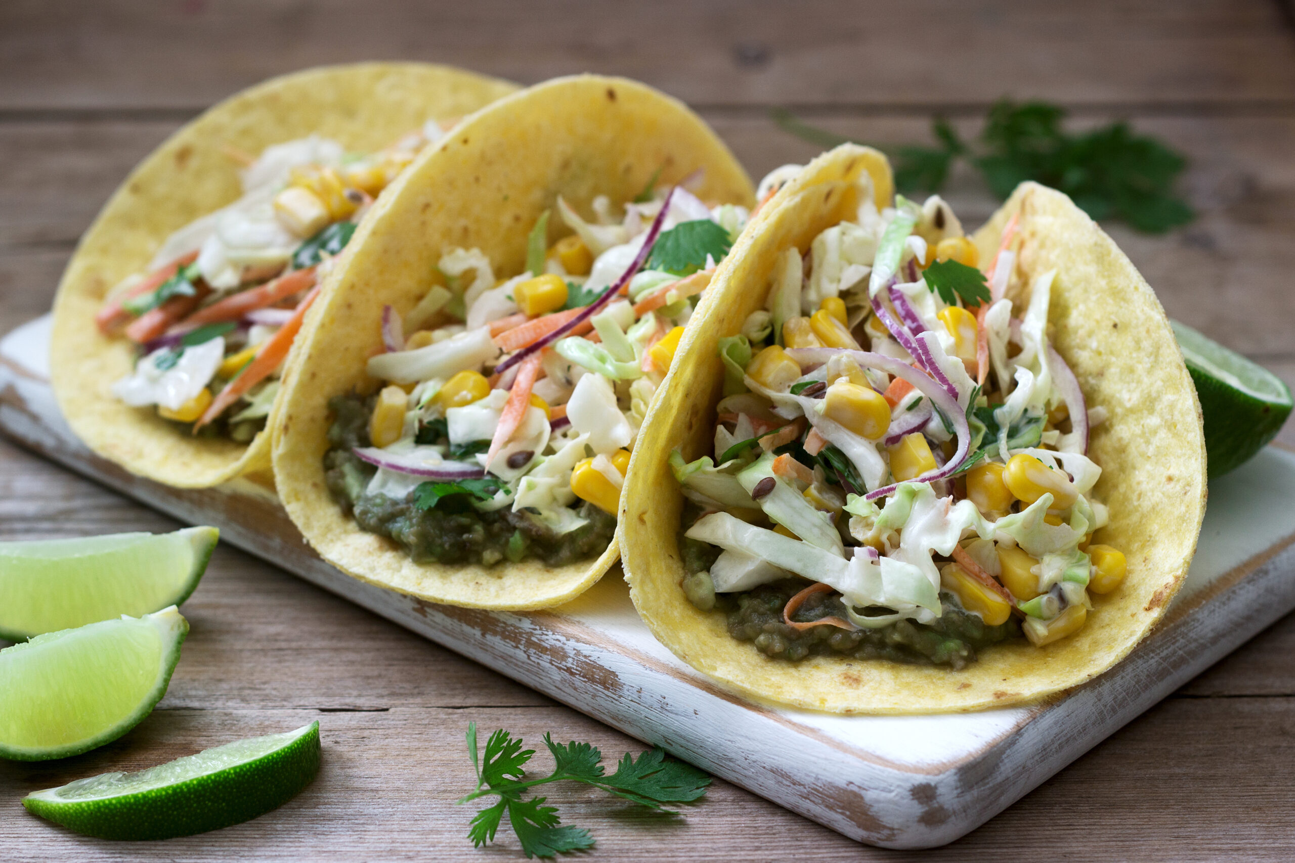 Vegetarian tacos stuffed with cabbage salad on a wooden background. Rustic style, selective focus.