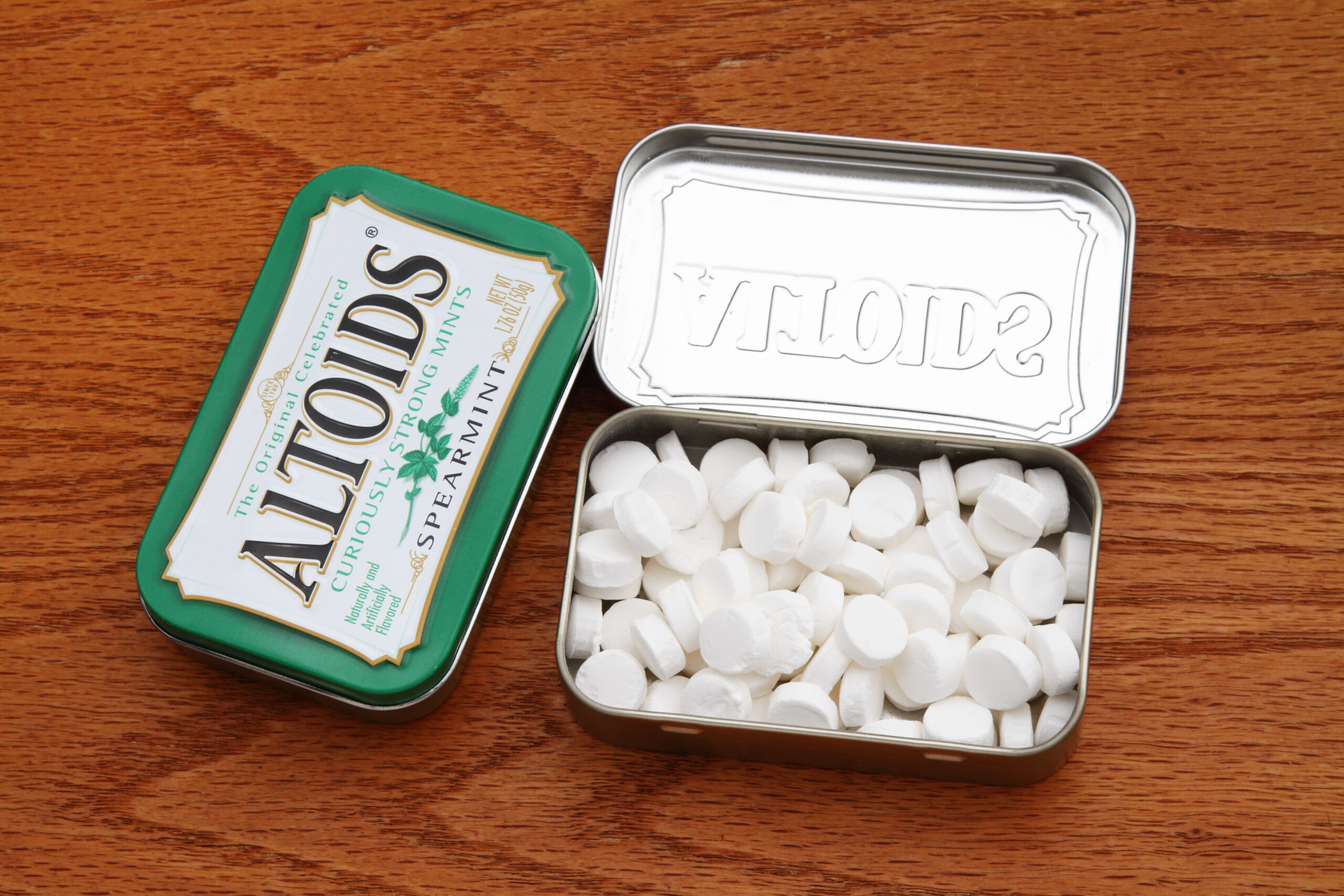 West Palm Beach, USA - May 28, 2013: Two metal tins of Altoids Curiously Strong Mints. The closed container holds spearmint mints. The white mints in the open canister are peppermint Altoids. Altoids are distributed by Callard and Bowser.