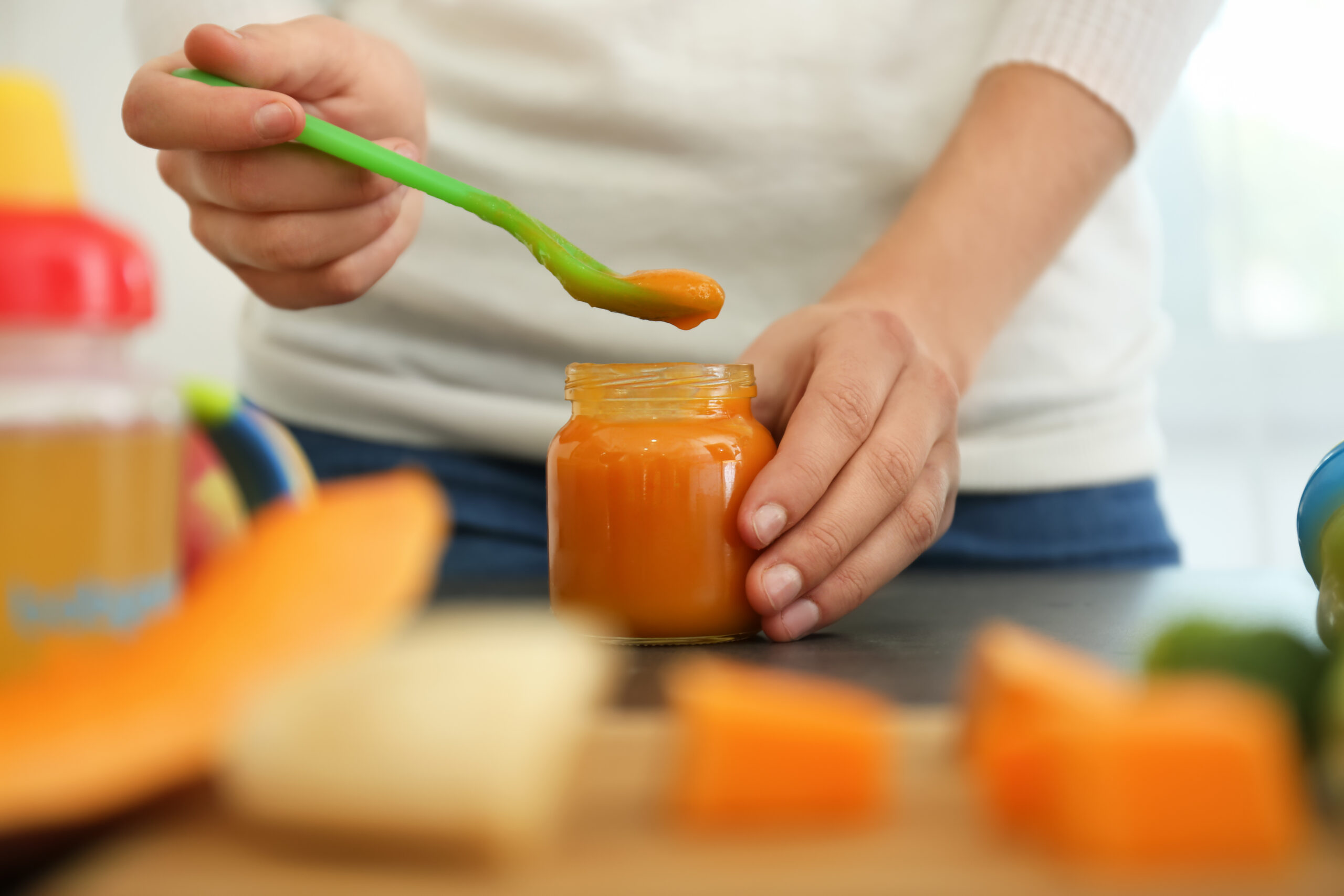 Woman preparing healthy baby food in kitchen, closeup