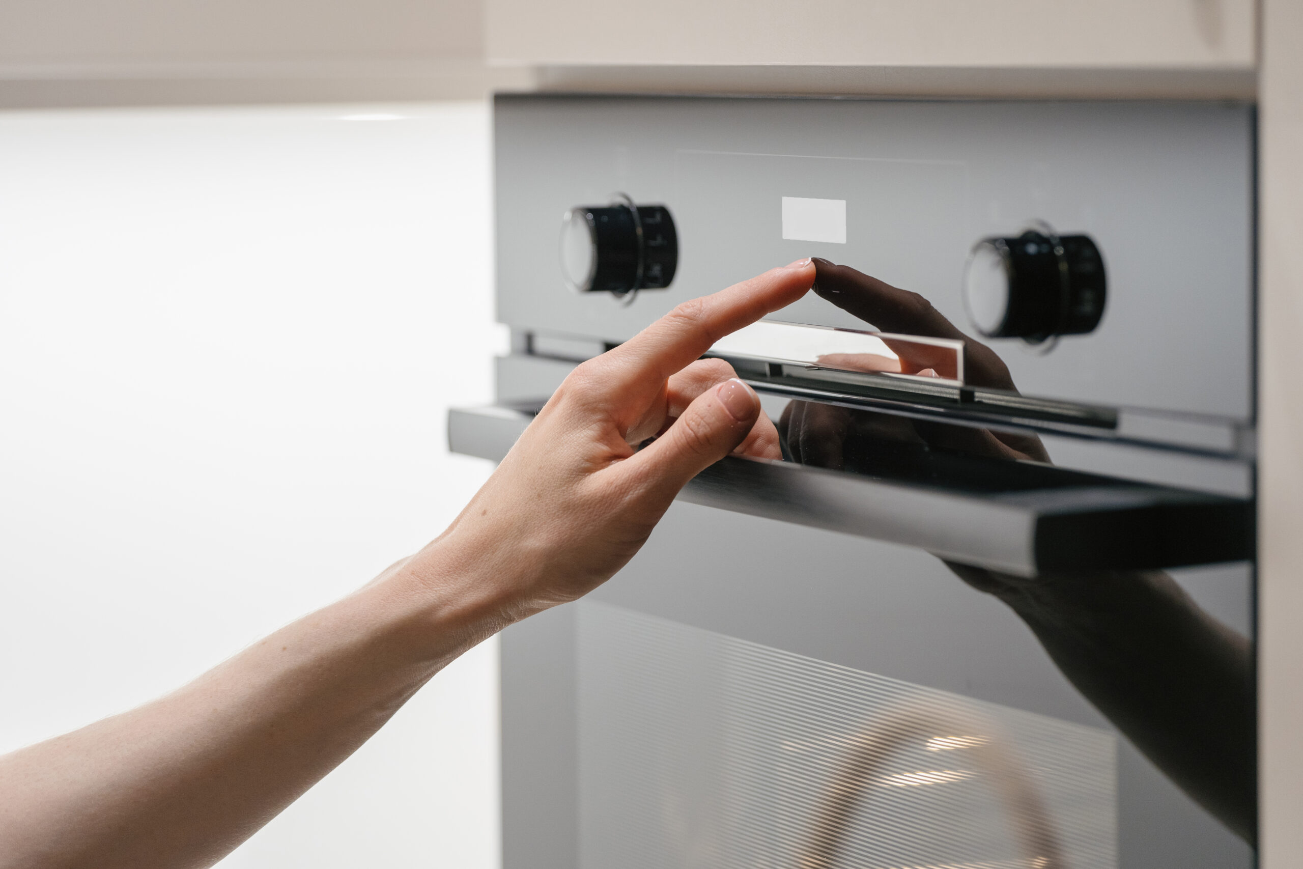 Woman press button on touchscreen display at modern electric oven. Housewife using control panel at built-in microwave with different cooking mode. Female checking temperature on household equipment