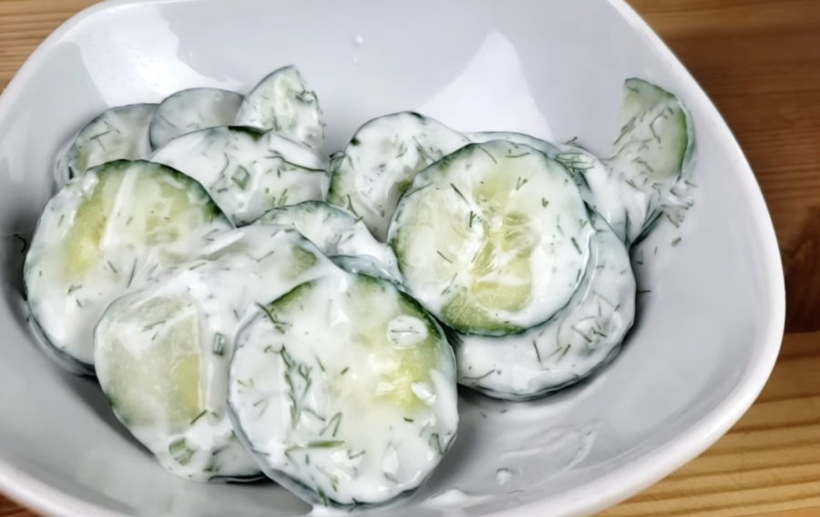 White bowl of creamy cucumber dill salad. Photo from YouTube video "Creamy Cucumber Dill Salad," posted by Mama Boi's Kitchen.