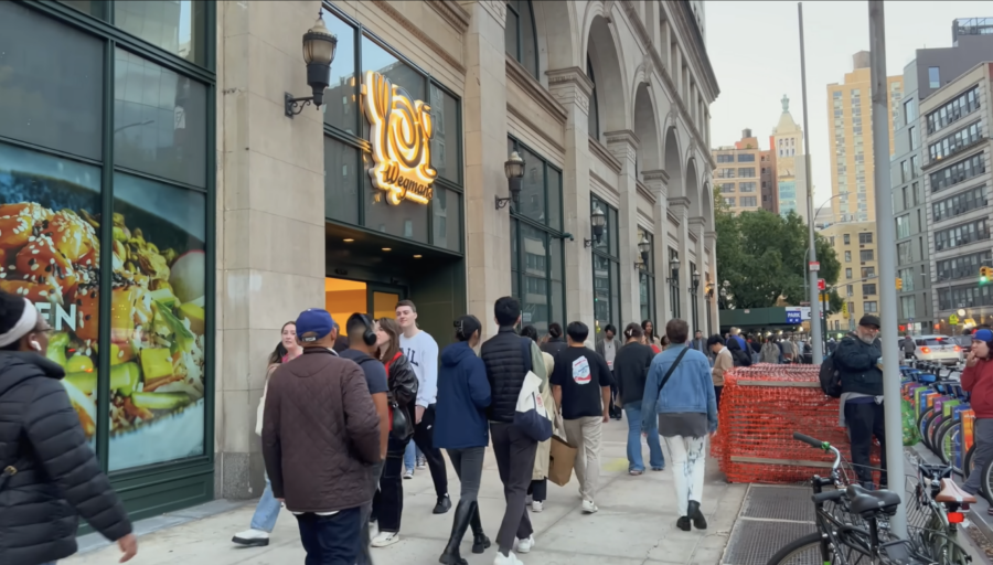 Wegman's storefront in NYC with people walking by, from YouTube video by ActionKid