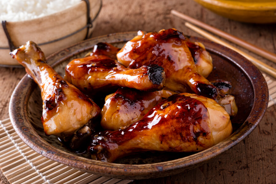 A bowl of honey garlic chicken drumsticks with rice.