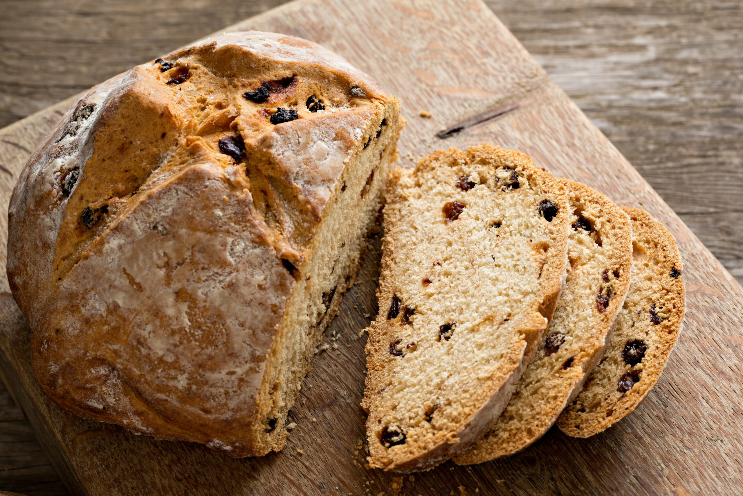 An overhead close up shot of a partially sliced Irish soda bread on an old wooden cutting board.