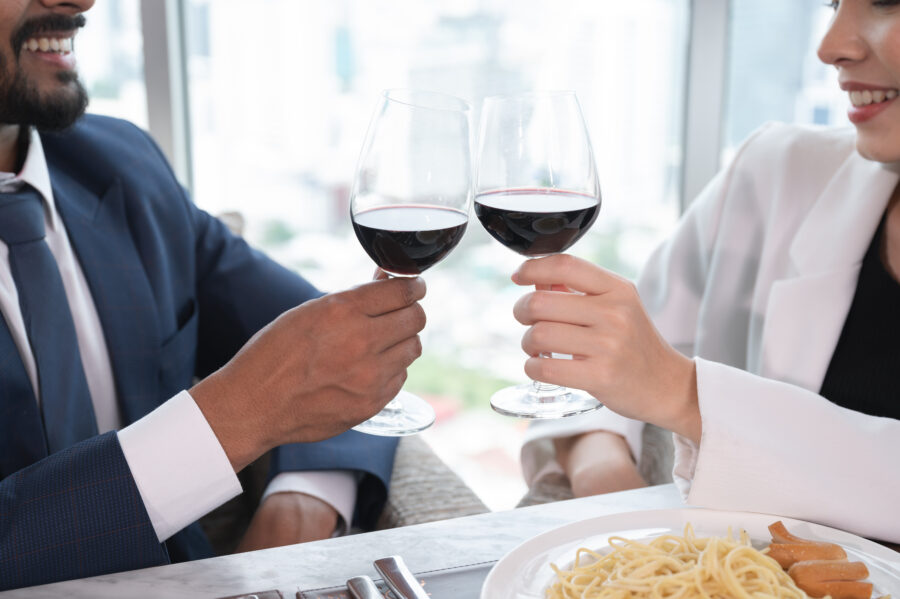 Asian businesswoman and Arab businessman cheers with husband at restaurant and city out of window background