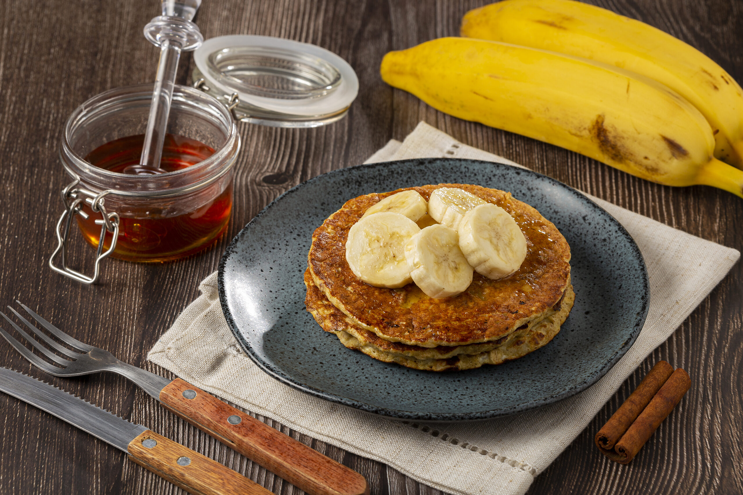 Banana oat pancakes topped with sliced bananas and honey.