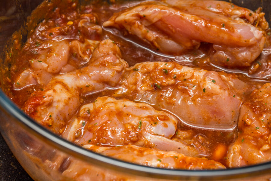 Close up and selective focus of tender, juicy and succulent chicken thighs marinading in a spicy and zingy sauce