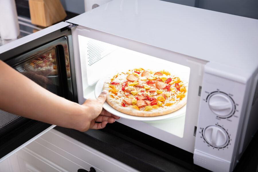 Close-up Of Woman Baking Pizza In Microwave Oven