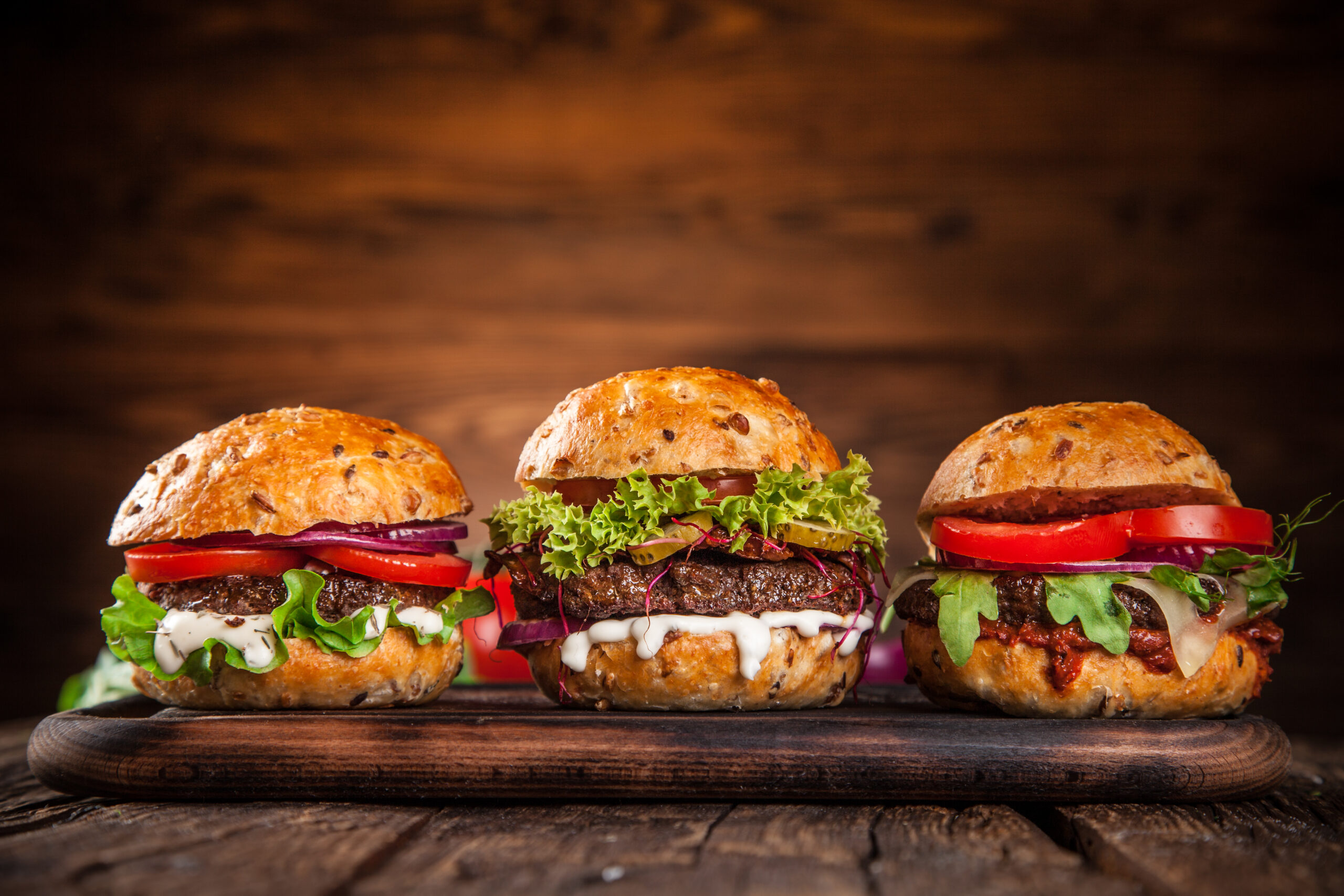 Close-up of home made burgers on wooden table.