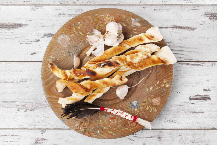 pizza sticks on wooden plate on white wooden background. 