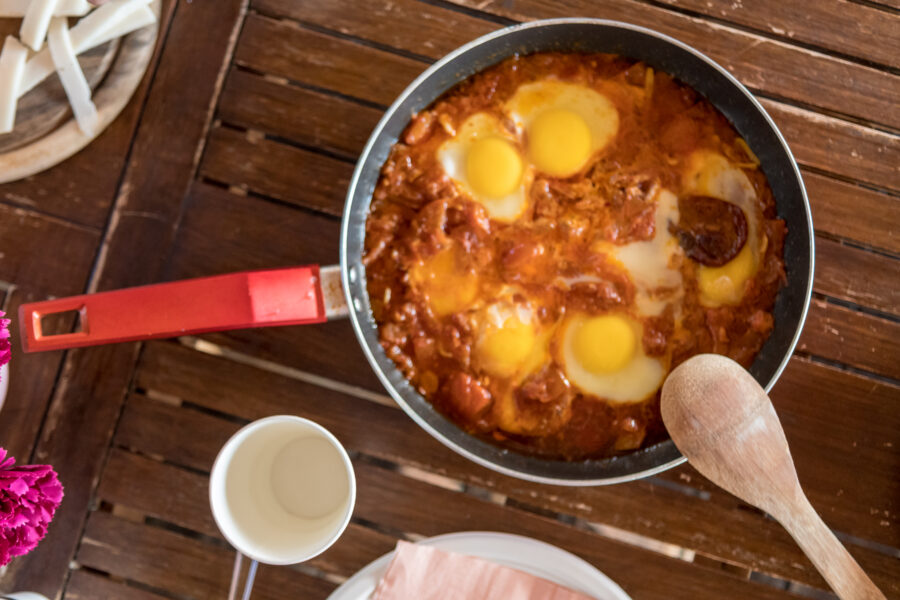 pan of shakshuka with spoon and drink