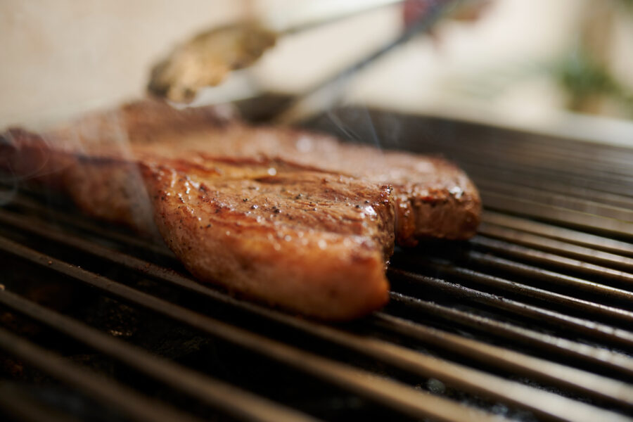 flipping a steak on a grill