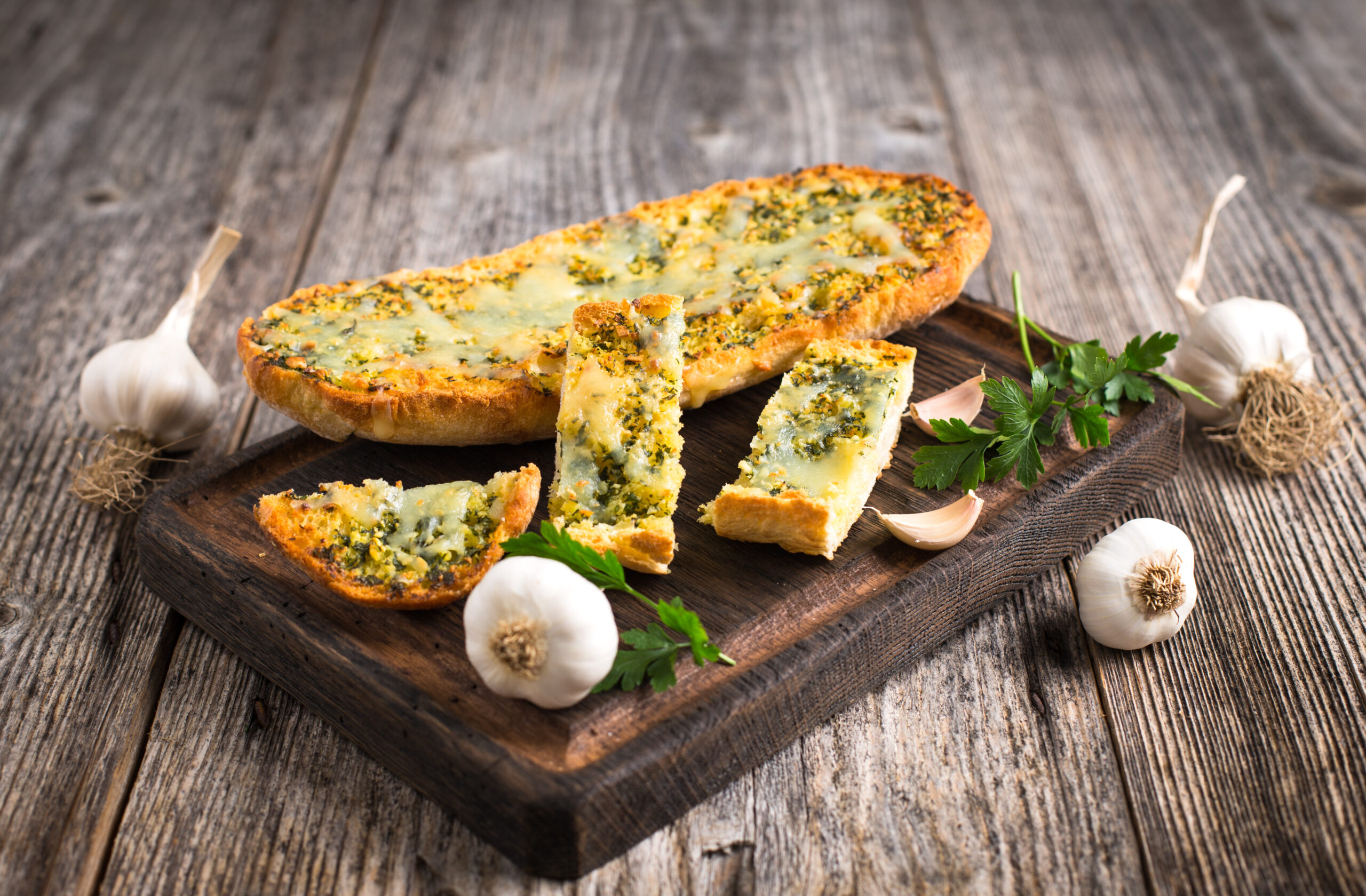 Fresh garlic bread with cheese and spices on the wooden table