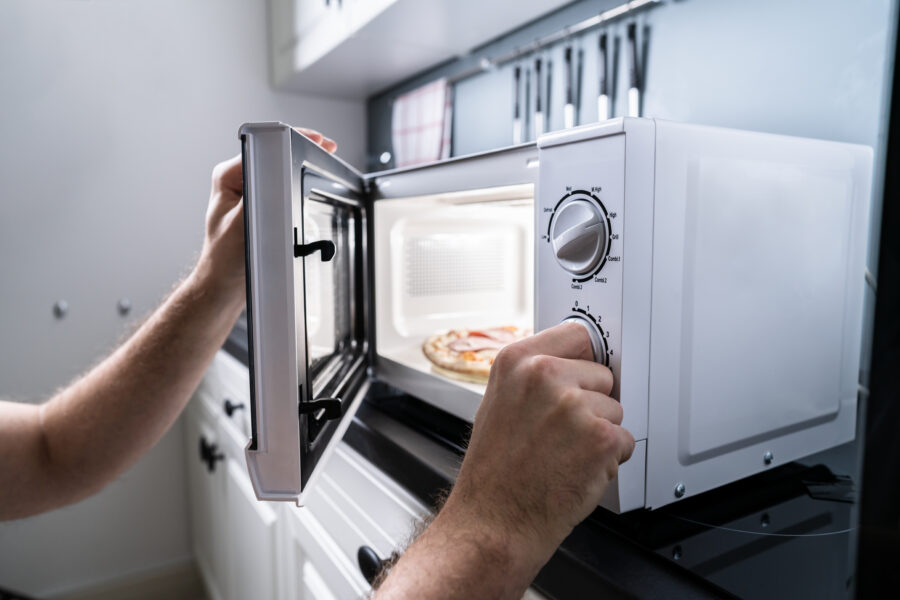 Human Hands Baking Pizza In Microwave Oven