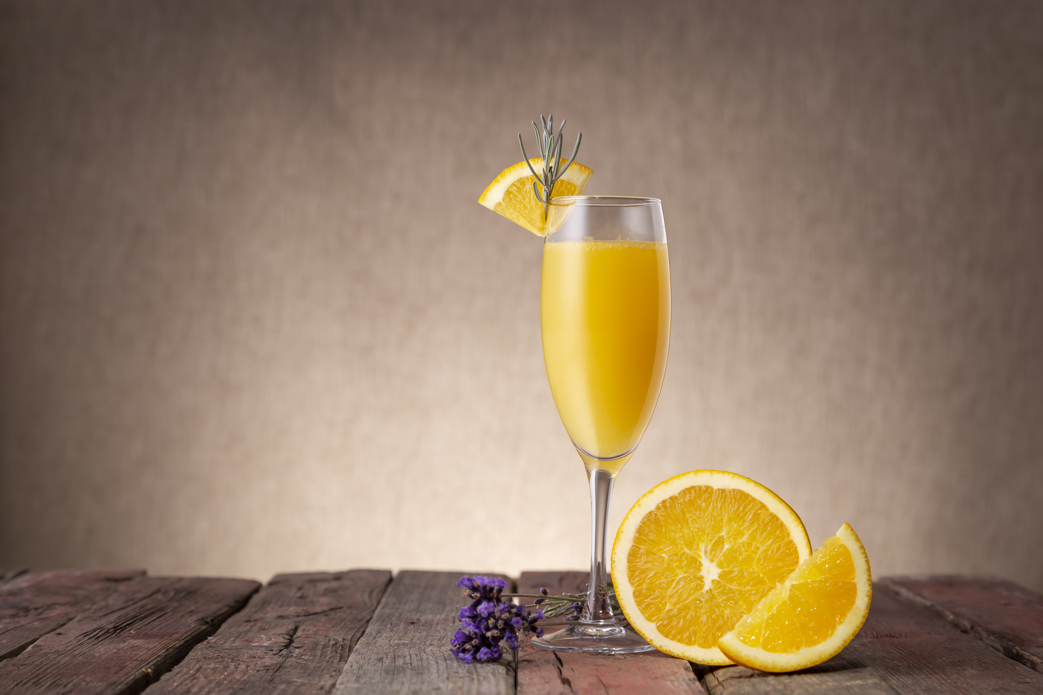 Mimosa cocktail in champagne glass with orange juice and sparkling wine decorated with lavender leaves and orange slices