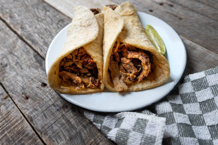 Arabes tacos on white plate, with a checkered napkin, on wooden background