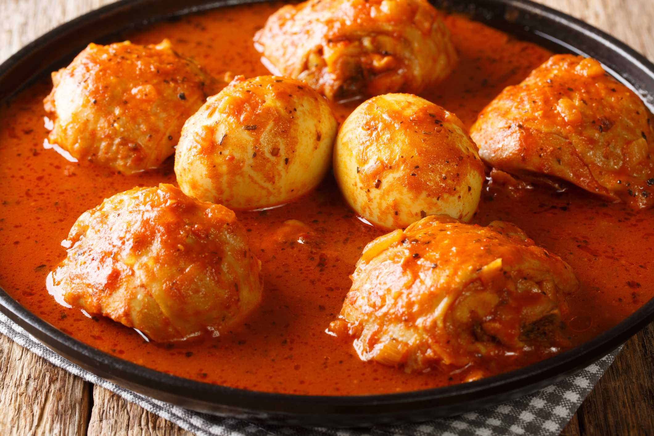 African Doro Wat from chicken thighs with eggs in a spicy sauce close-up in a plate on the table. horizontal