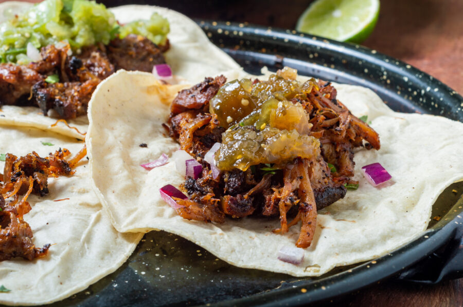 Carnitas tacos with red onion and raw salsa verde. 