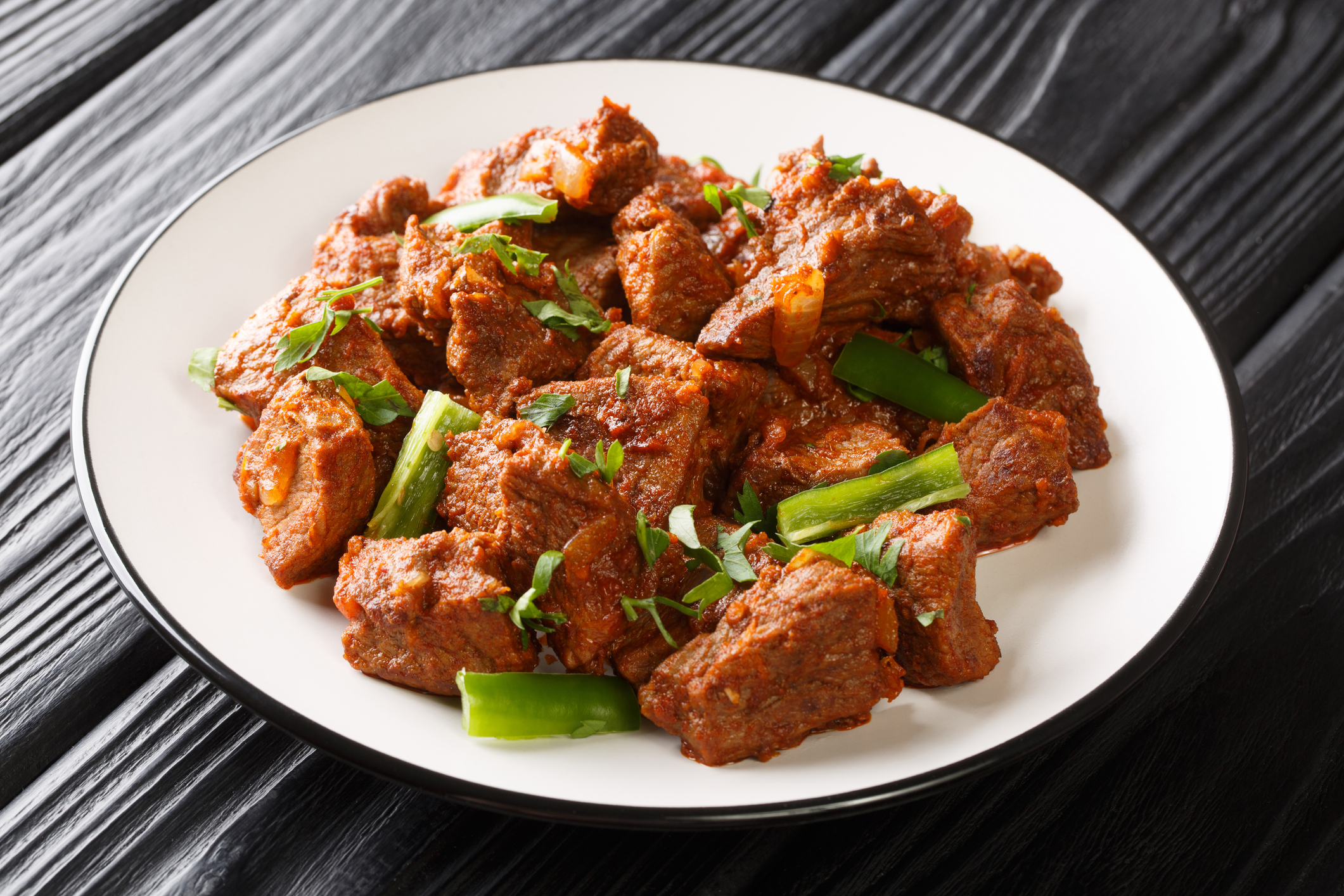 Ethiopian beef tibs seasoned with berbere spice and spicy awaze paste closeup in the plate on the table. Horizontal