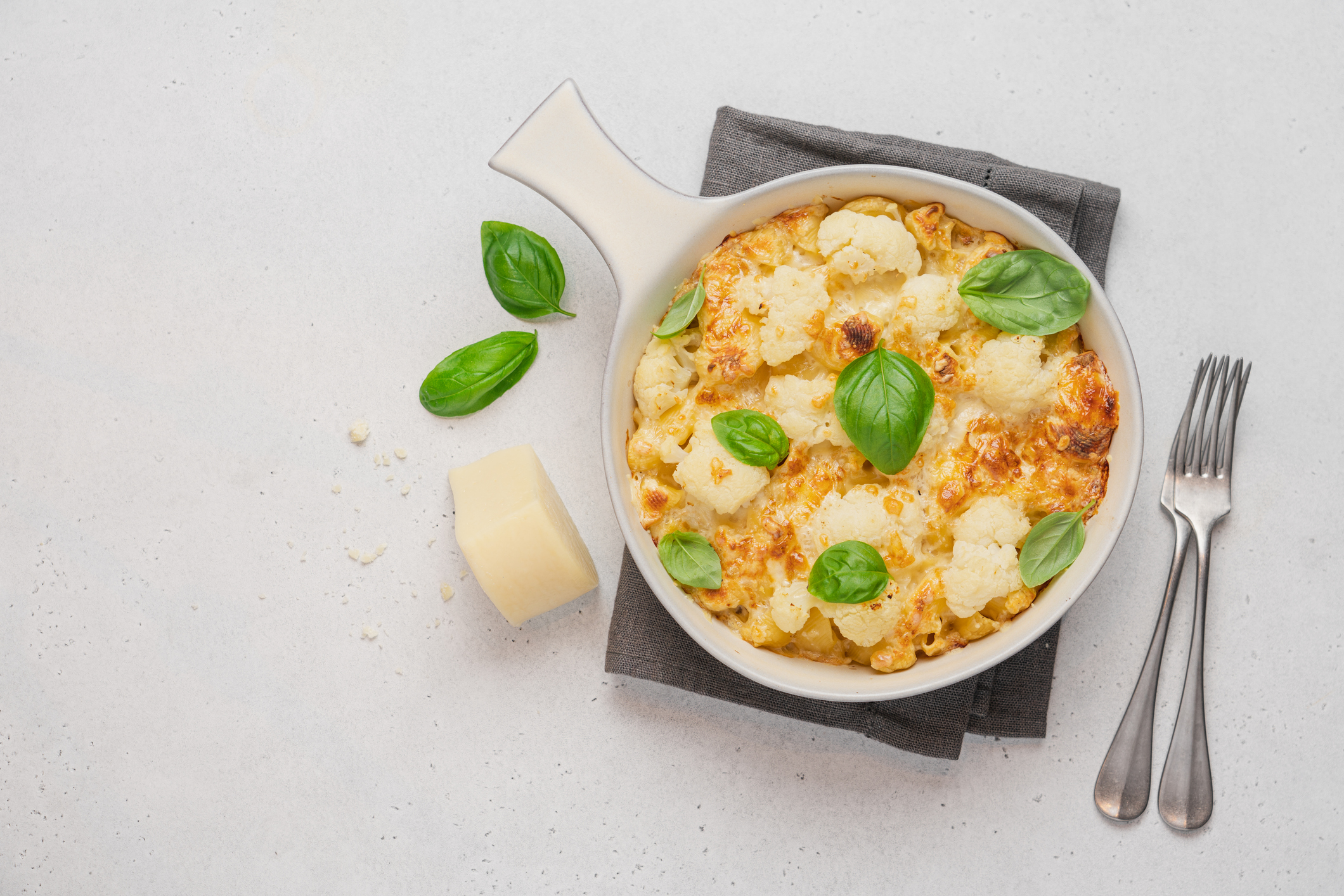 Baked pasta with cheese and cabbage in ceramic pot on white background. American cuisine concept