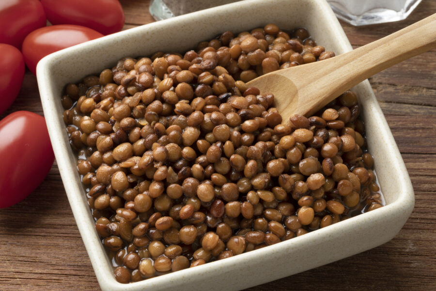 Bowl with preserved steamed small brown lentils close up