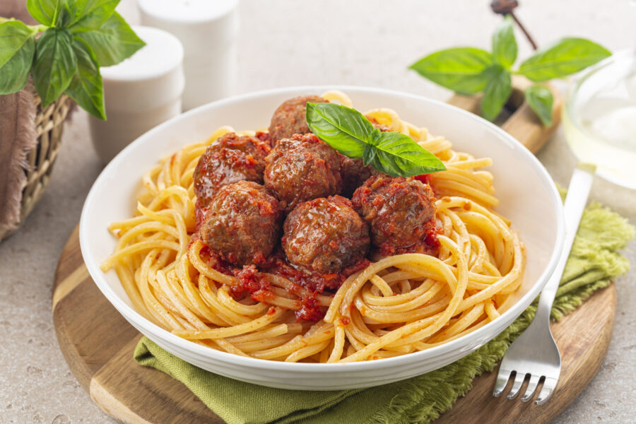 Spaghetti and beef Meatballs with tomato sauce in white dish on wooden rustic board. Close-up.