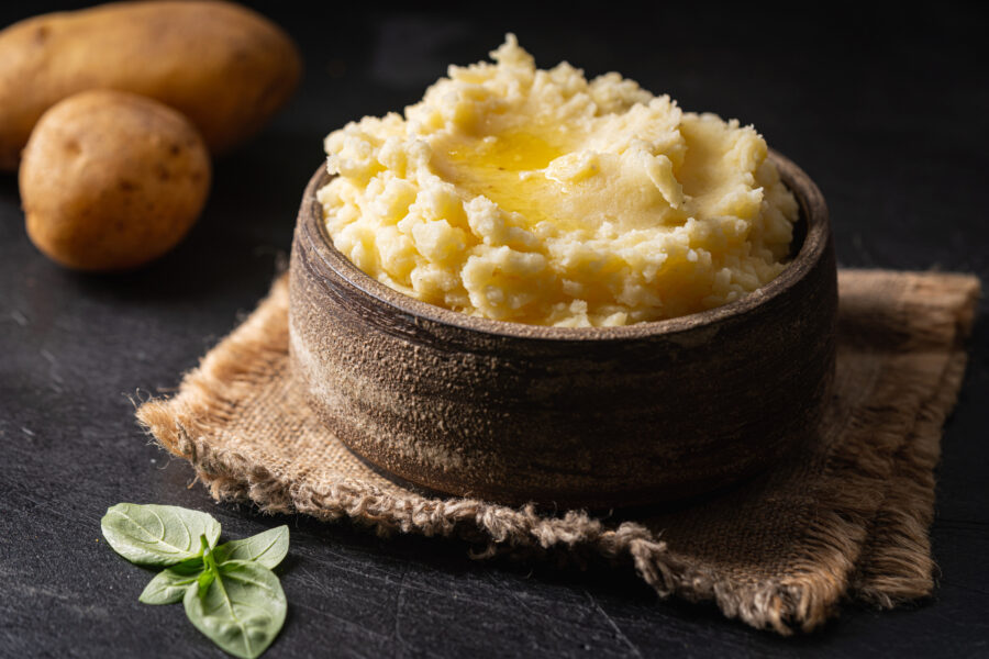 Mashed potatoes in ceramic bowl on wooden rustic table. 