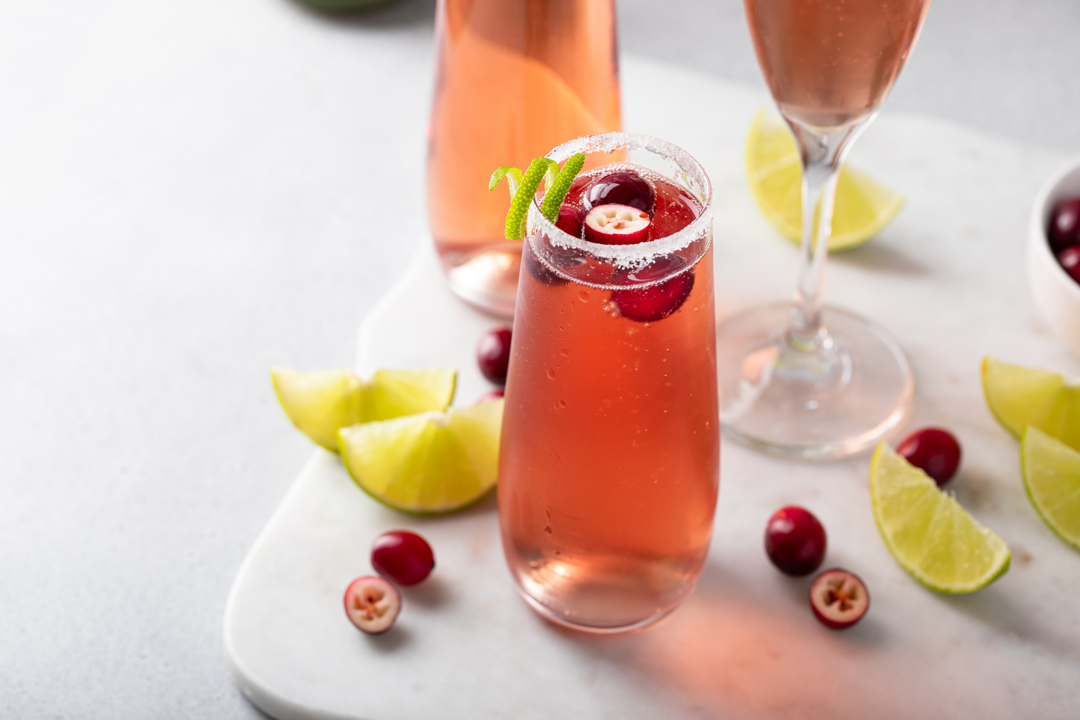 Christmas mimosa with cranberry juice and lime, garnished with lime twist, festive sparkling wine or rose cocktail idea