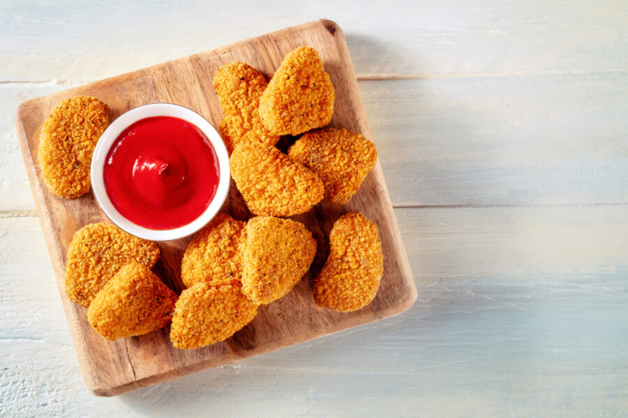 Chicken nuggets with ketchup sauce on a rustic wooden table, shot from above