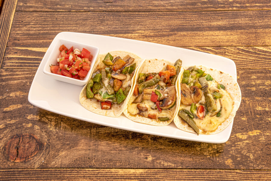 Mexican tacos of nopales, mushrooms and vegetables with fundos cheese and pico de gallo on white tray