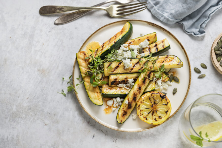 Grilled zucchini and feta cheese salads with lemon dressing on a plate high angle view on table