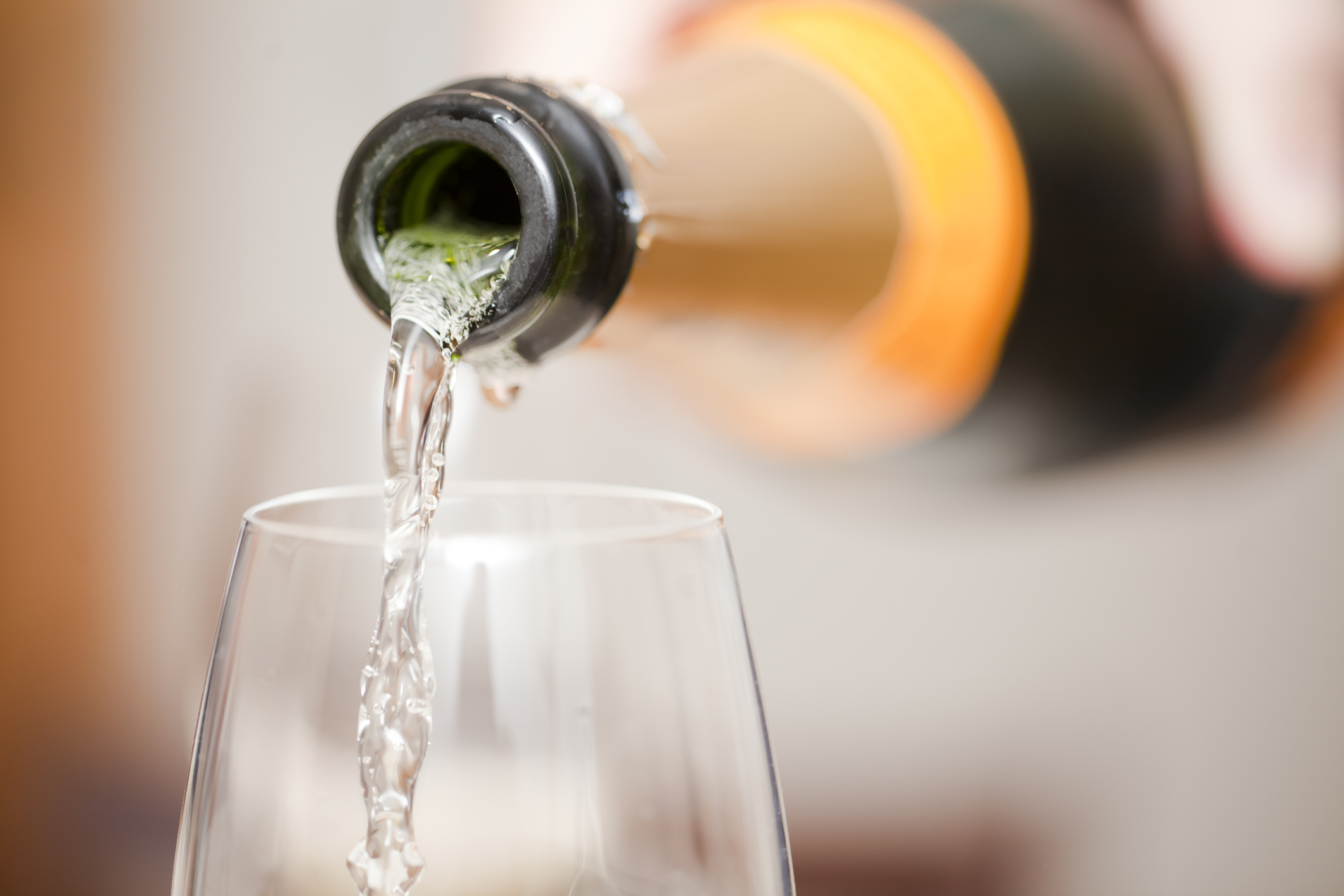 Close up of bottle of champagne, white wine,  pouring into a glass. Horizontal view with copy space on the right.