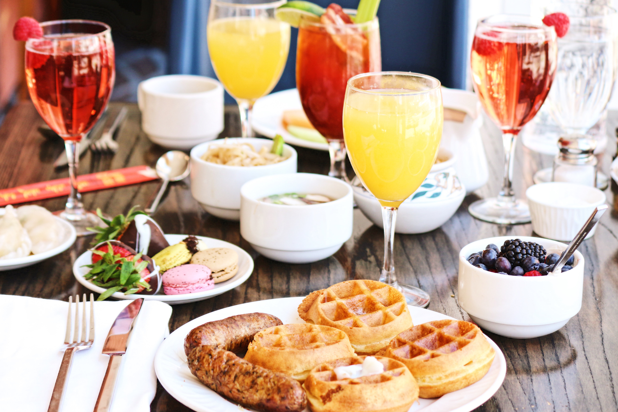 A brunch spread at a hotel with waffles, sausage, blueberries, chocolate covered strawberries.