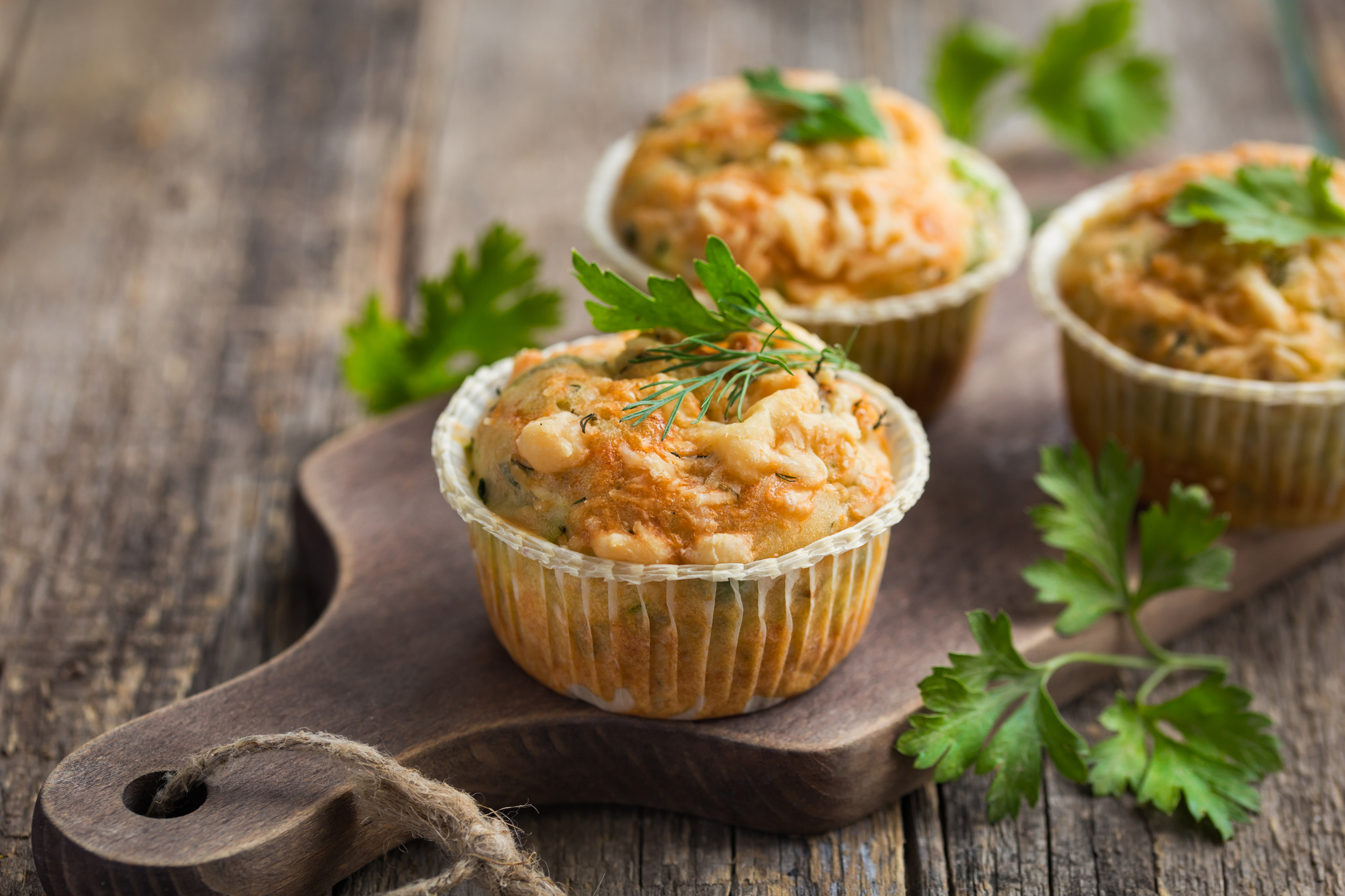 savory muffins with zucchini and cheese on wooden background