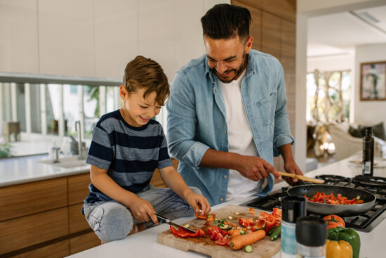 Father and son preparing food at home kitchen.