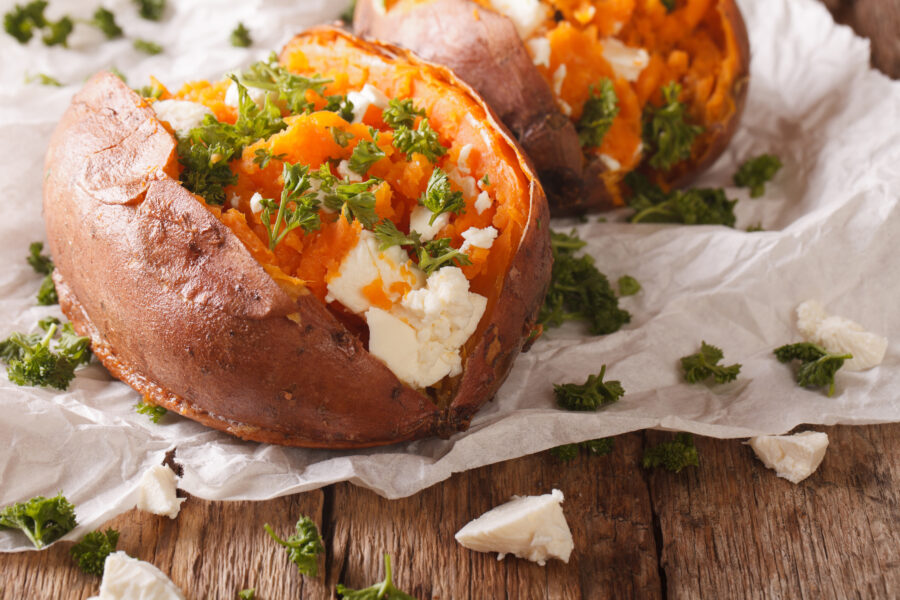 baked sweet potato stuffed with feta cheese and parsley close-up on the table. Horizontal