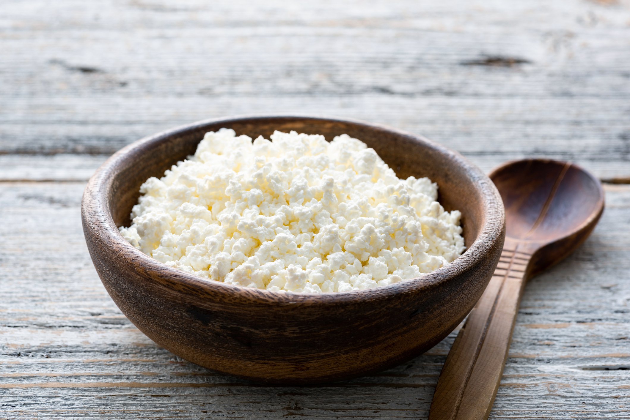 Ricotta cheese, cottage cheese farmers cheese, curd or tvorog in a wooden bowl. Closeup view, selective focus