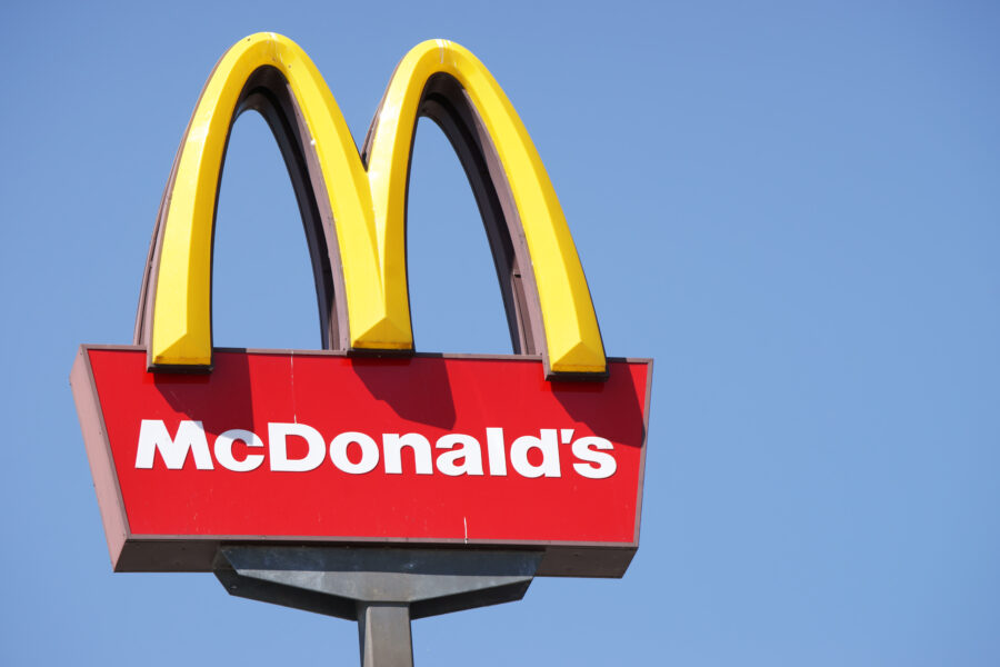 Close-up of McDonalds outdoor sign with  typical rounded yellow M letter against cloudless blue sky. Sign is positioned on the left side of image.