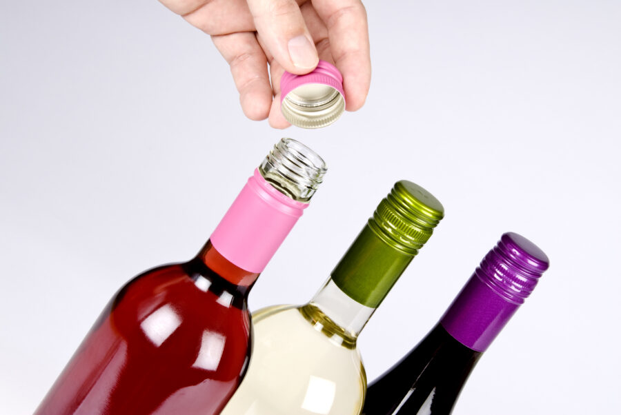 Man's hand opening a bottle of wine with a screwcap.